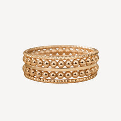 Stack of gold beaded bracelets on a white background