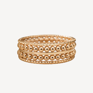 Stack of gold beaded bracelets on a white background