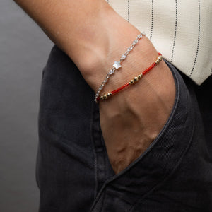 Close-up of a wrist wearing two bracelets against a neutral background