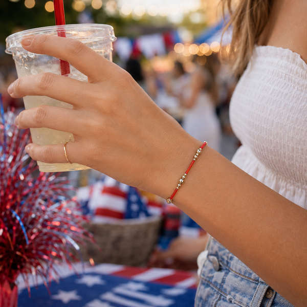 Person holding a drink with a red straw at a festive outdoor event.