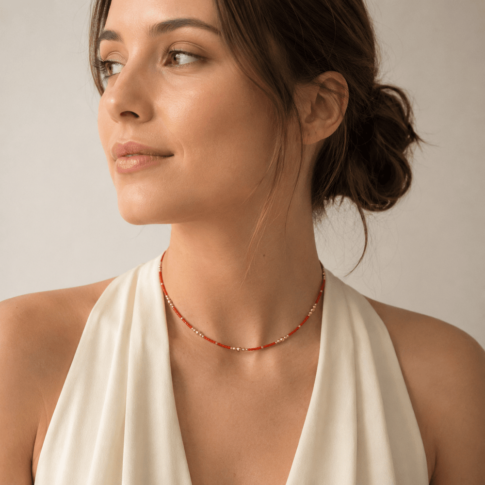 Necklace with orange beads and gold accents on a white background