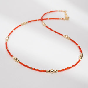 Necklace with red beads and gold accents on a white background