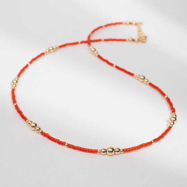 Necklace with red beads and gold accents on a white background