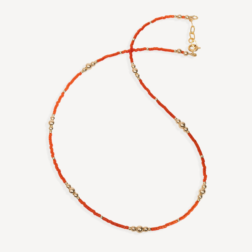 Necklace with orange beads and gold accents on a white background