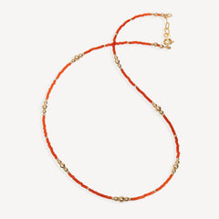 Necklace with orange beads and gold accents on a white background