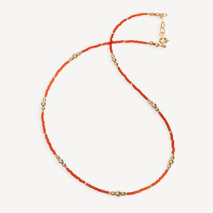Necklace with orange beads and gold accents on a white background