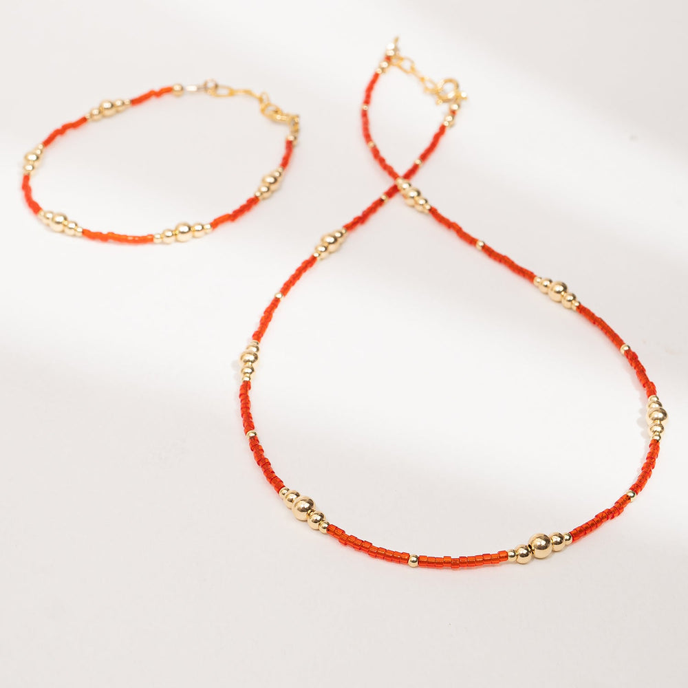 Necklace with orange beads and gold accents on a white background