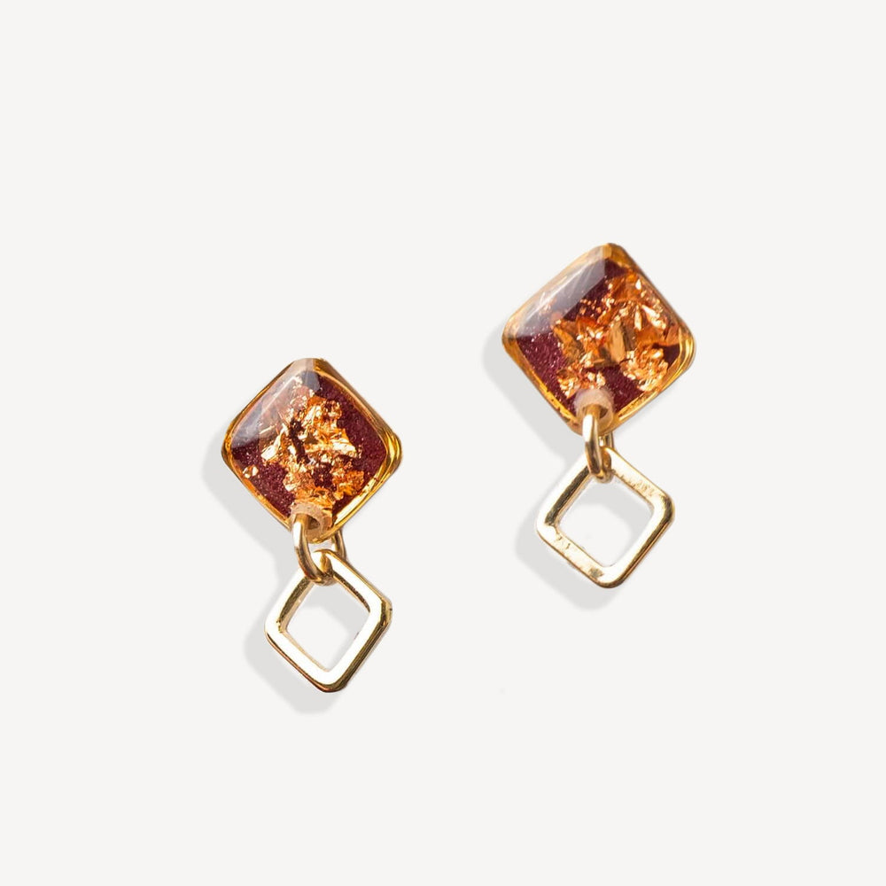 Gold earrings with square-shaped amber stones on a white background