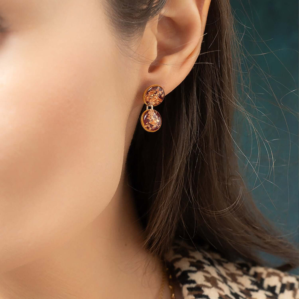 Pair of earrings with gold and copper color scheme on a white background