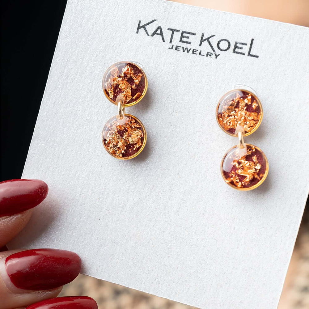 Pair of earrings with gold and copper color scheme on a white background