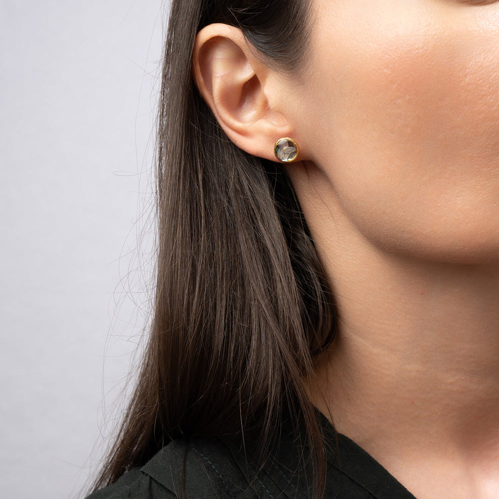 Pair of round earrings with gold frame and multicolored stone center on a white background