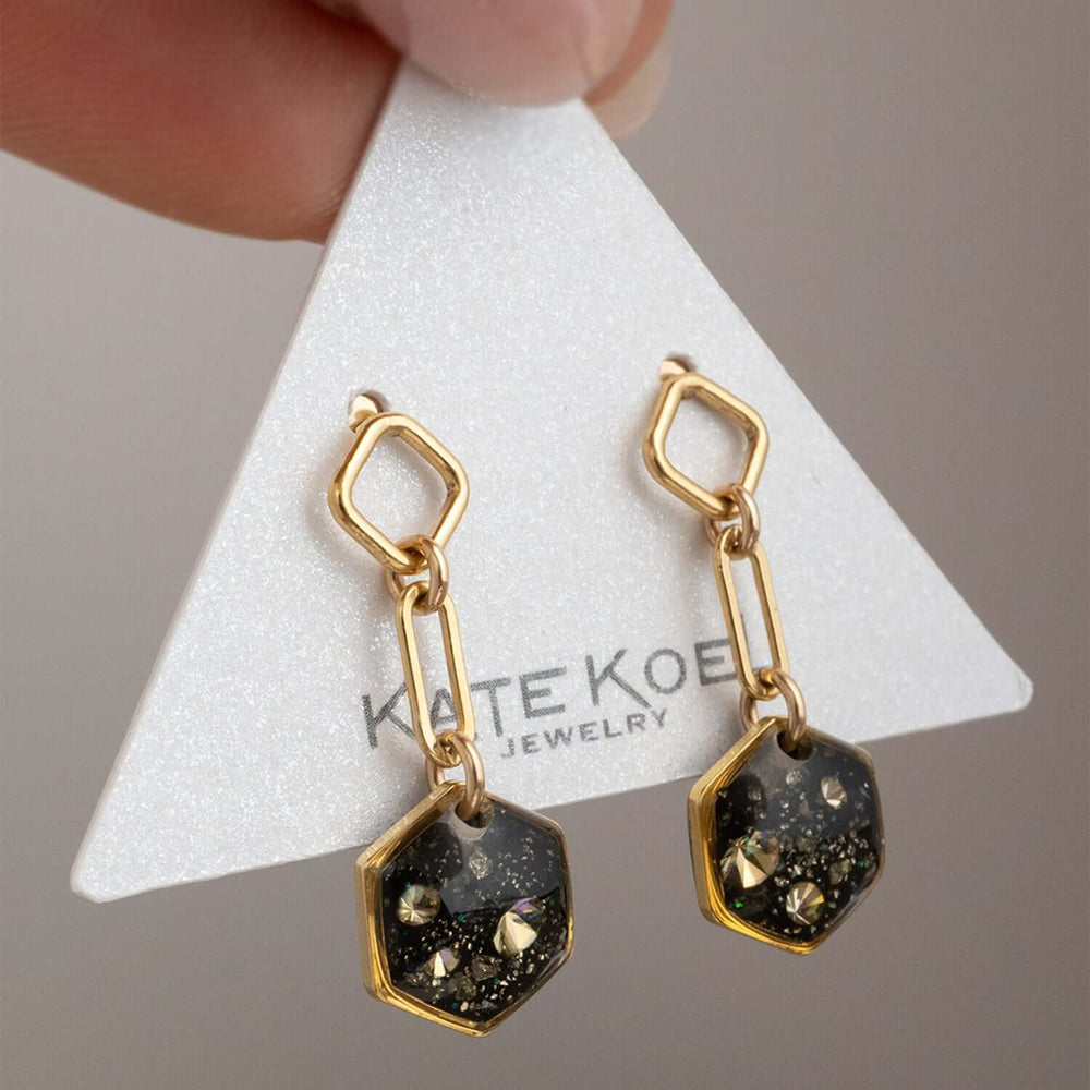Gold and black hexagonal earrings on a white background