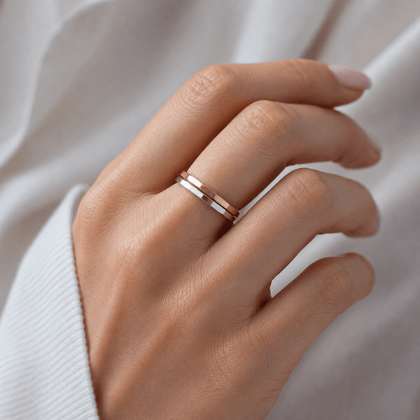 Hand wearing a rose gold ring on a neutral background