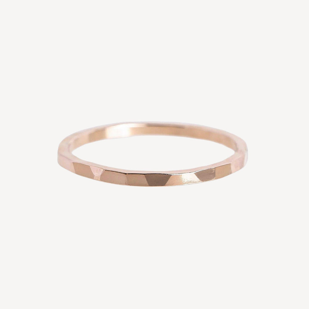 Hand wearing a gold ring on a plain background