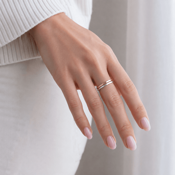 Hand wearing a silver ring on a neutral background