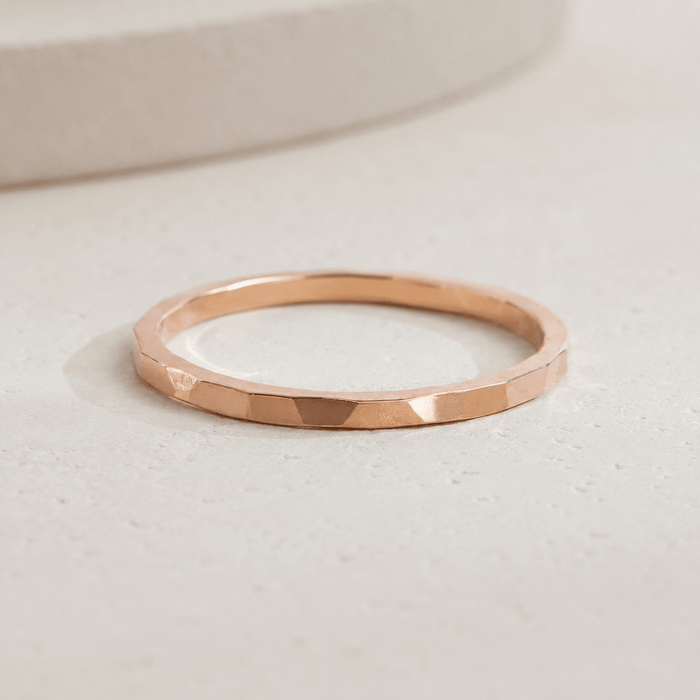 Hand wearing a gold ring on a plain background