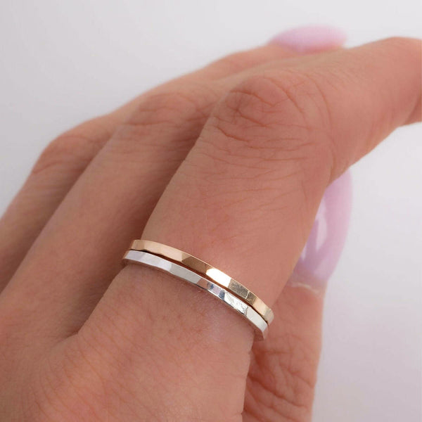 Close-up of a hand wearing two gold rings on a light background