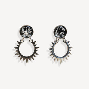 Pair of sun-shaped earrings with black and silver details on a white background
