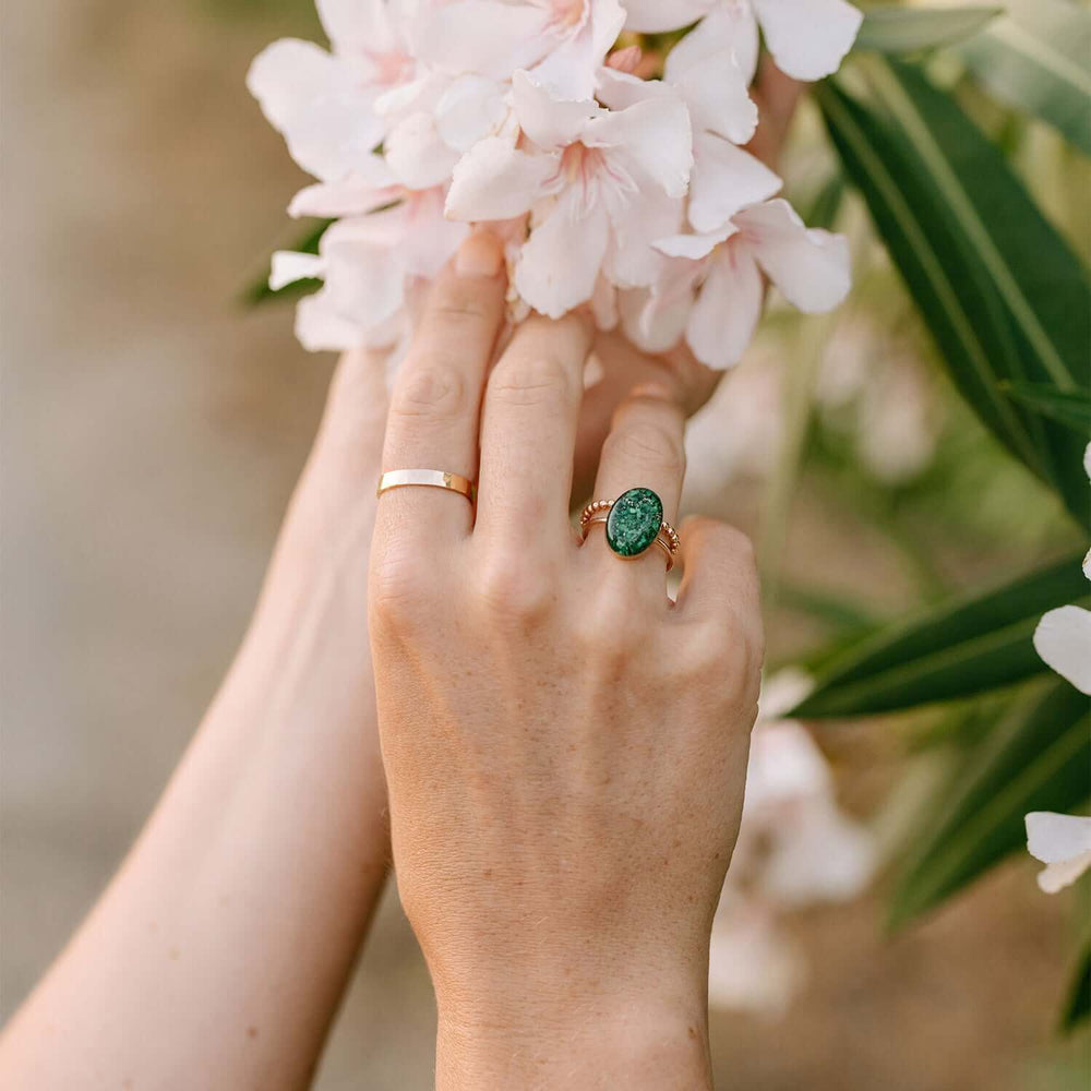 Two green gemstone rings with gold and silver bands on a white background