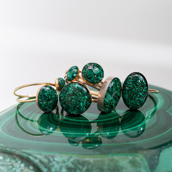 Green gemstone rings on a reflective green surface