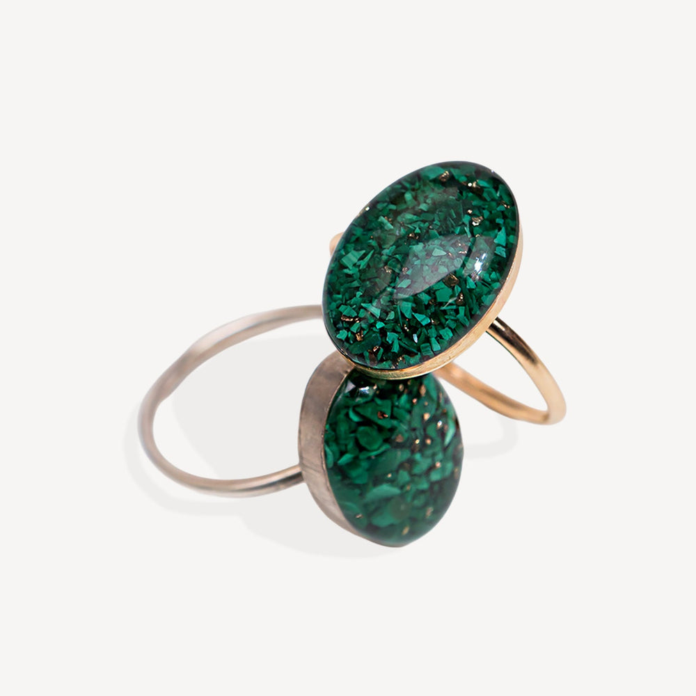 Two green gemstone rings with gold and silver bands on a white background