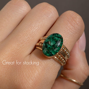 Green gemstone ring on a finger with text 'Great for stacking'.