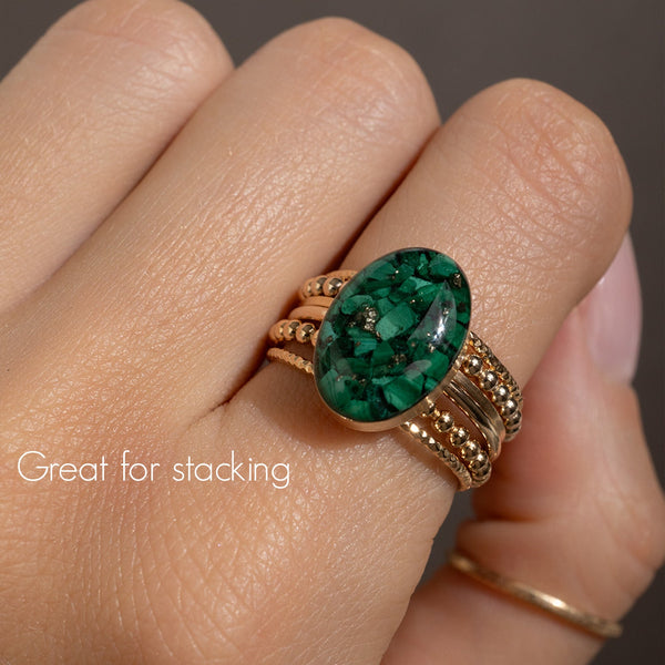 Green gemstone ring on a finger with text 'Great for stacking'.