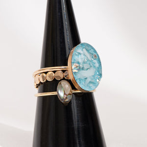 Set of three rings with different designs on a black stand against a white background
