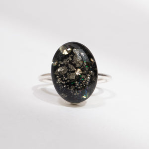 Silver ring with an oval black stone on a white background