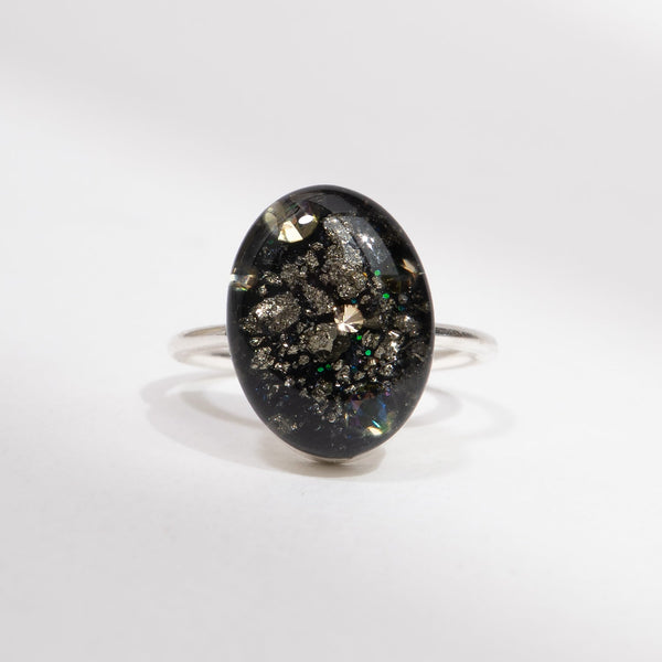 Silver ring with an oval black stone on a white background