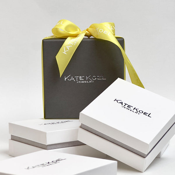 Kate Koel jewelry boxes with a yellow ribbon on a white background