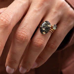 Close-up of a hand wearing a decorative ring with a large gemstone.
