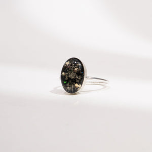 Silver ring with an oval black stone on a white background