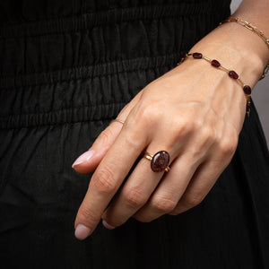 Hand wearing a ring and bracelet with a dark background