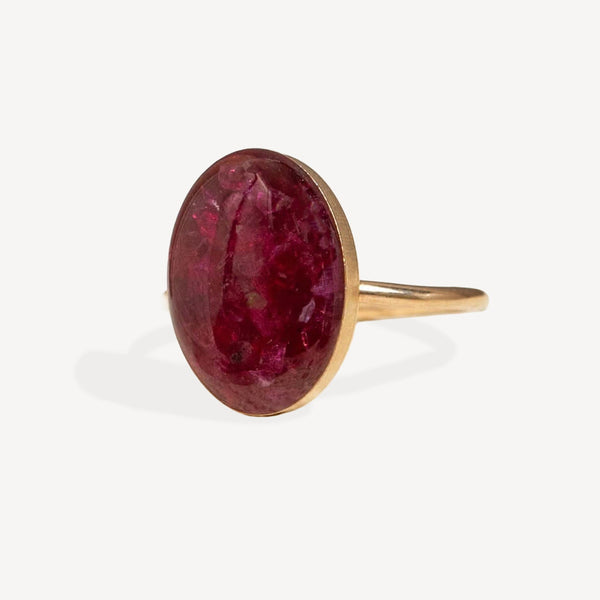 Gold ring with a large red gemstone on a white background
