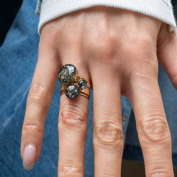 Close-up of a hand wearing two rings with gemstones against a blurred background