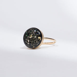 Gold ring with a black gemstone on a light gray background