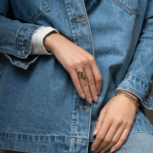Close-up of hands wearing rings and bracelets with a denim jacket.