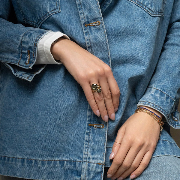 Close-up of hands wearing rings and bracelets with a denim jacket.