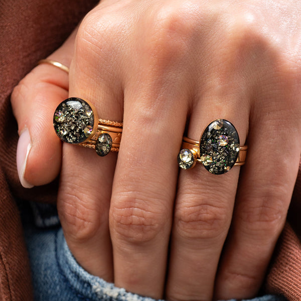 Close-up of a hand wearing two ornate rings with gemstones.