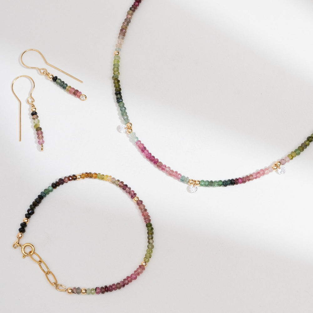 Multicolored beaded bracelet on a gold chain with a white background