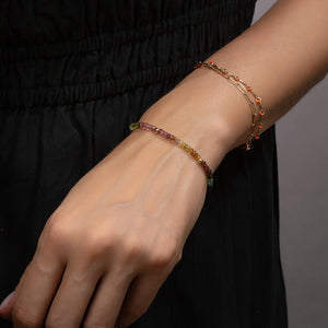 Close-up of a person's wrist wearing two beaded bracelets against a black background