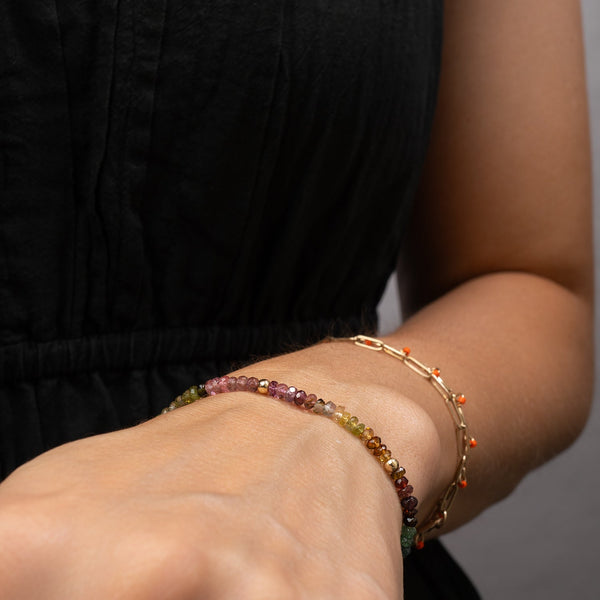 Close-up of a person's arm wearing two beaded bracelets on a neutral background
