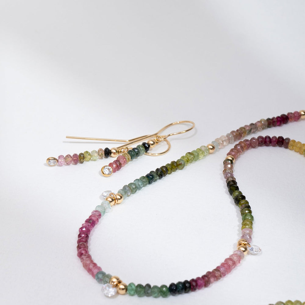 Gold earrings with multicolored gemstones on a white background