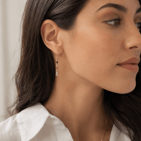 Close-up of a woman wearing gold gemstone watermelon tourmaline earrings 