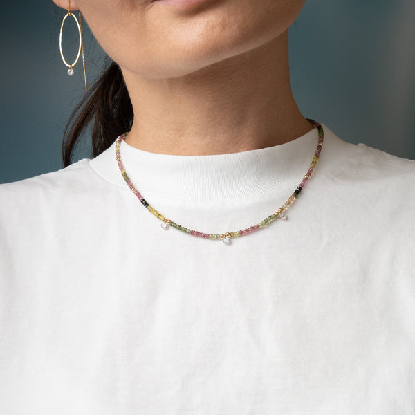 Close-up of a person wearing a colorful beaded necklace against a neutral background