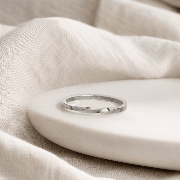 Silver ring on a beige stone surface with a soft beige fabric background