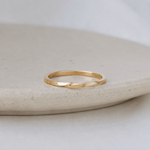 Gold ring on a light stone surface with a neutral background