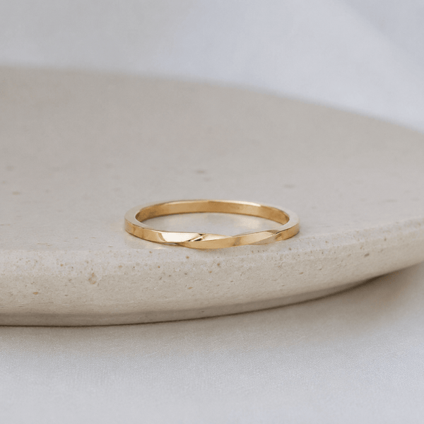 Gold ring on a light stone surface with a neutral background